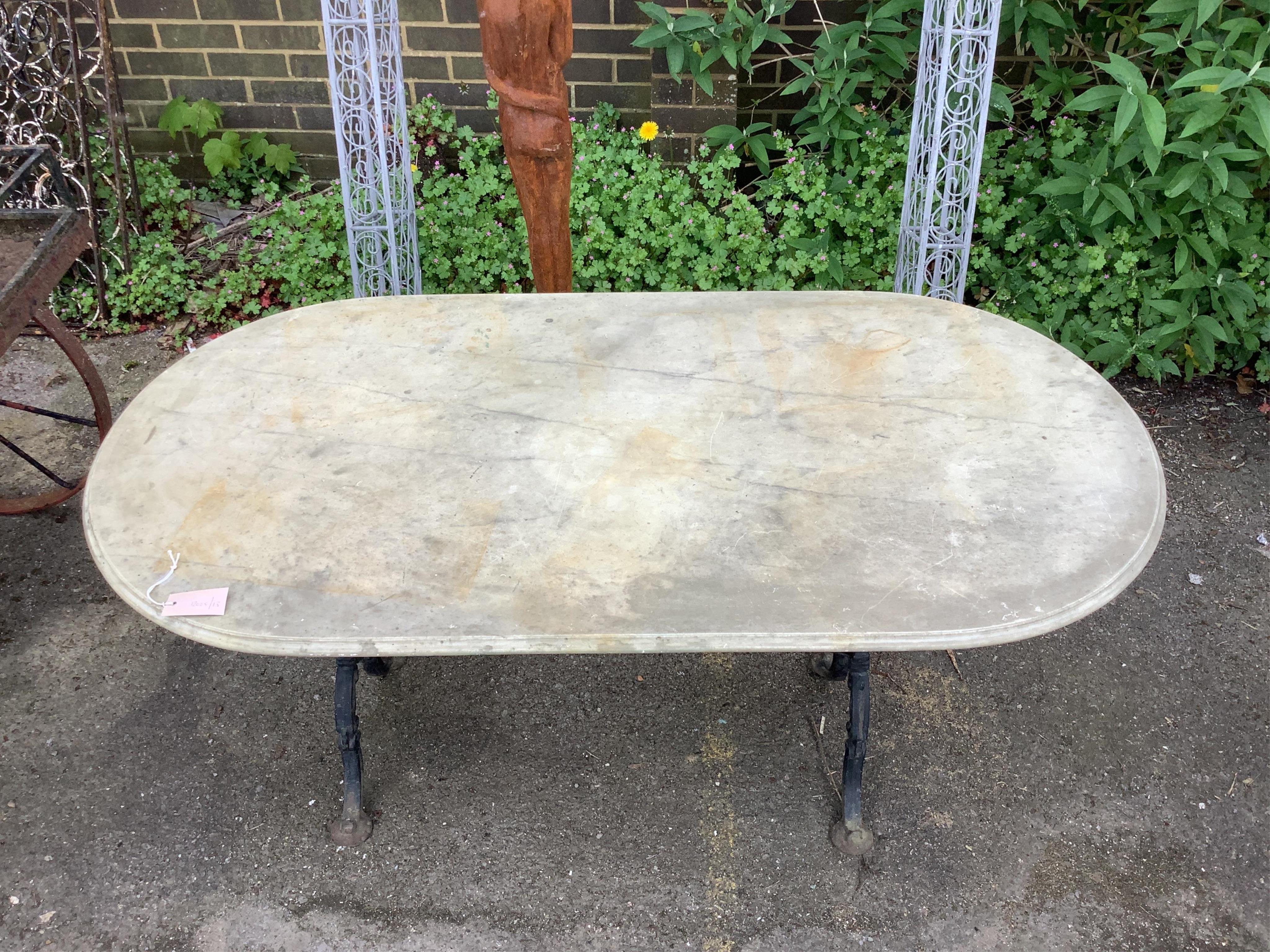 An oval reconstituted marble and wrought iron garden table, width 135cm, depth 69cm, height 70cm